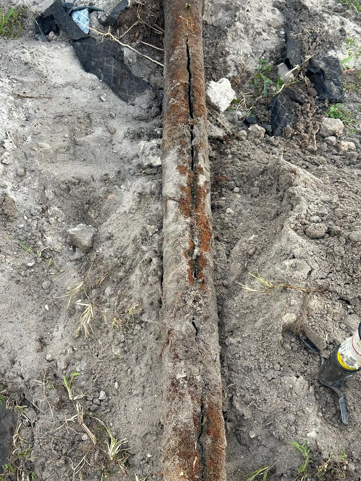 The rusted-through cast iron sewer line in the open trench